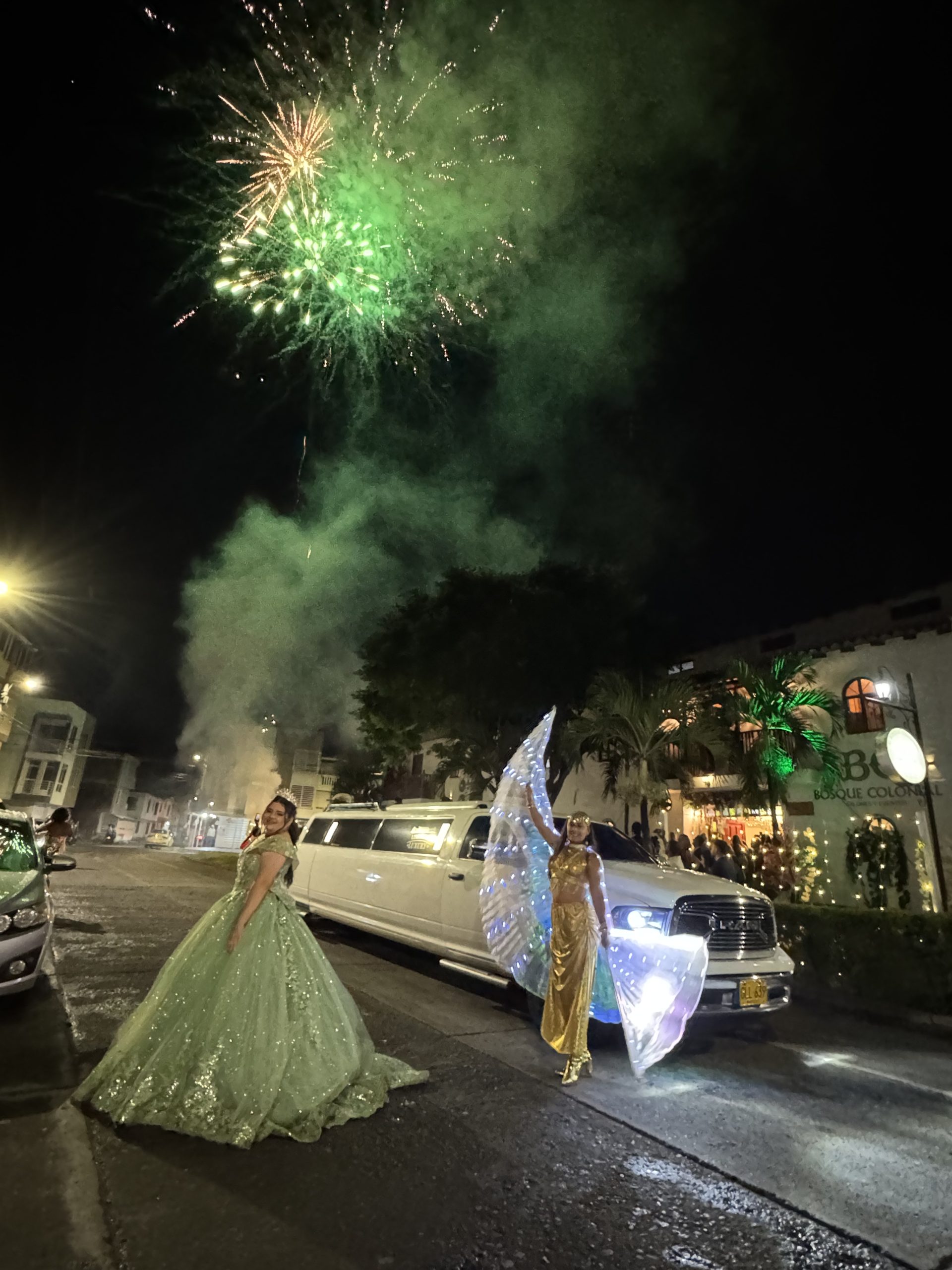 A quinceañera beside the limousine on a night of fireworks